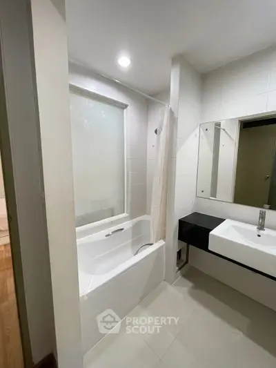 Modern bathroom with sleek design featuring a bathtub and stylish sink area.