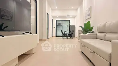 Modern living room with sleek furniture and open layout, featuring a stylish TV setup and dining area.