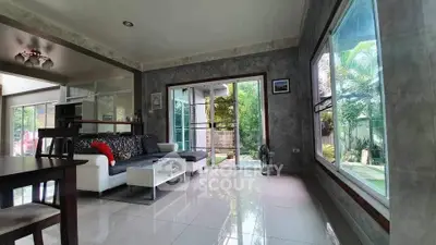 Spacious living room with modern decor and large windows overlooking a lush garden.