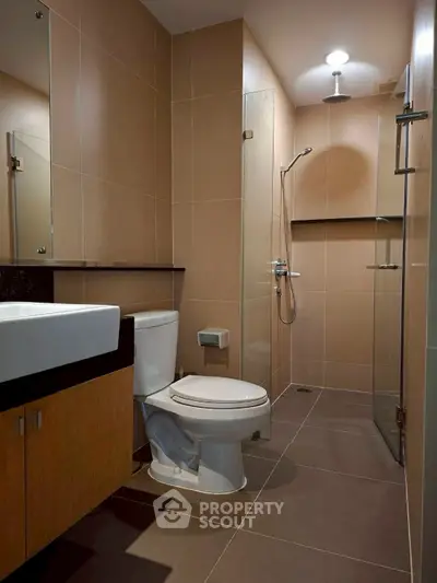 Modern bathroom with sleek design and glass shower enclosure in a contemporary apartment.