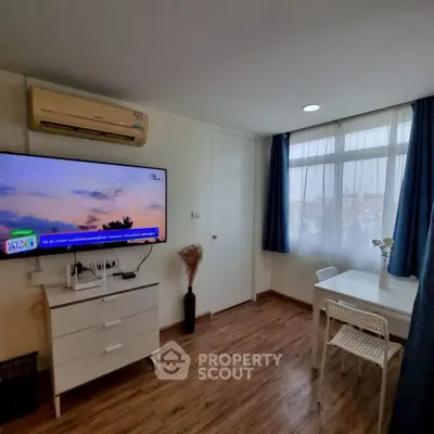 Cozy living room with modern decor, wall-mounted TV, and dining area in a bright apartment.