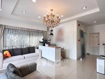 Elegant living room with chandelier and modern decor, featuring a cozy seating area and natural light.