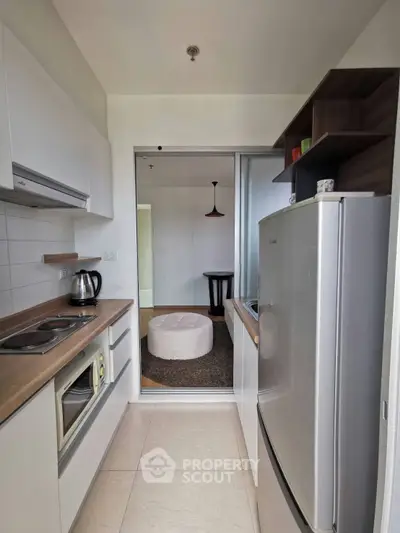 Modern kitchen with sleek appliances and open layout, featuring a cozy adjacent living area.