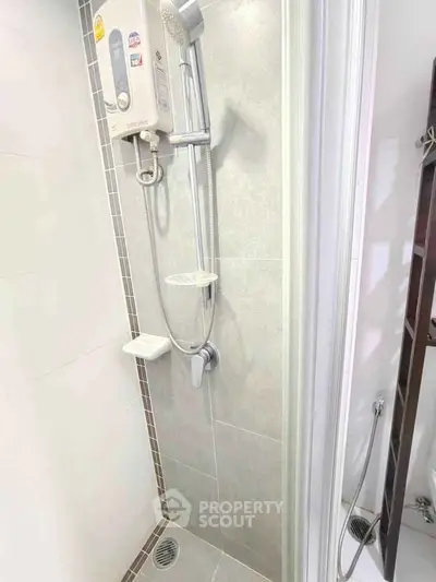 Modern bathroom shower area with sleek tiles and water heater.