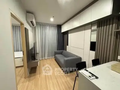 Modern living room with sleek design and open layout, featuring a cozy gray sofa and wall-mounted TV.