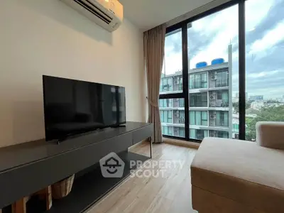 Modern living room with large window and city view, featuring sleek TV setup and air conditioning.