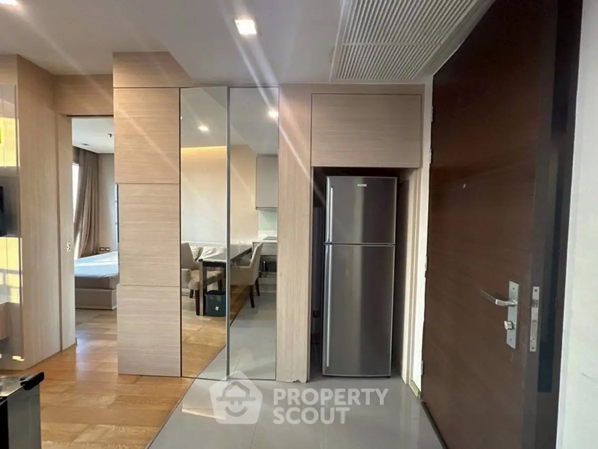 Modern apartment entrance with sleek fridge and mirrored walls