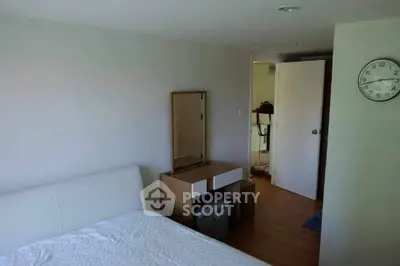 Cozy bedroom with modern furniture and wall clock, perfect for relaxation.