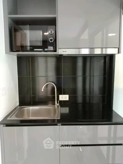 Modern compact kitchen with sleek cabinetry and built-in microwave