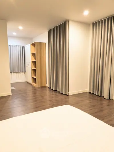 Spacious modern bedroom with elegant curtains and wooden flooring