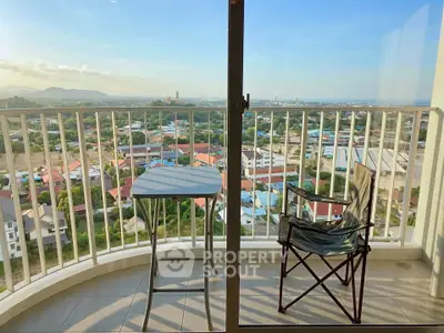 Stunning balcony view with seating overlooking cityscape and mountains, perfect for relaxation.