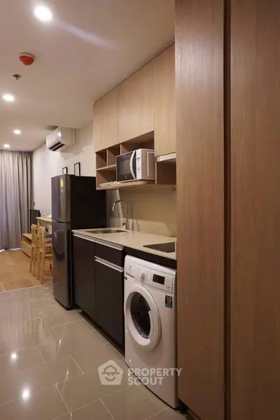 Modern kitchen with sleek appliances and wooden cabinetry in a stylish apartment.