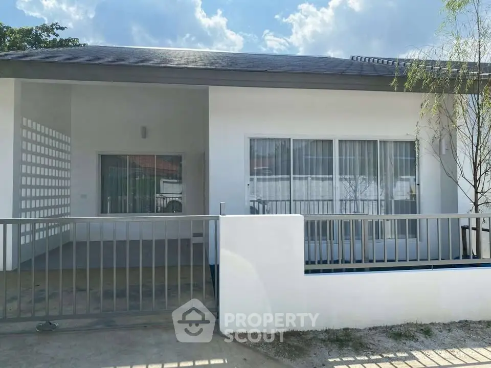 Modern single-story house with large windows and gated entrance, perfect for family living.