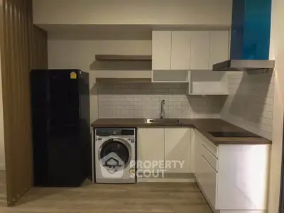 Modern kitchen with sleek cabinetry, washing machine, and fridge in compact layout.