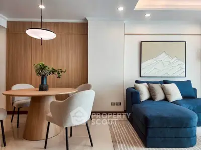 Modern living room with stylish blue sofa and elegant dining area, featuring contemporary lighting and decor.