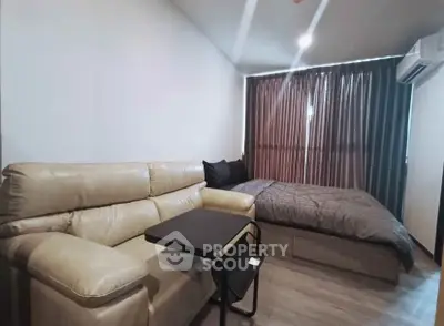 Modern studio apartment with cozy living area and comfortable bed, featuring sleek design and neutral tones.