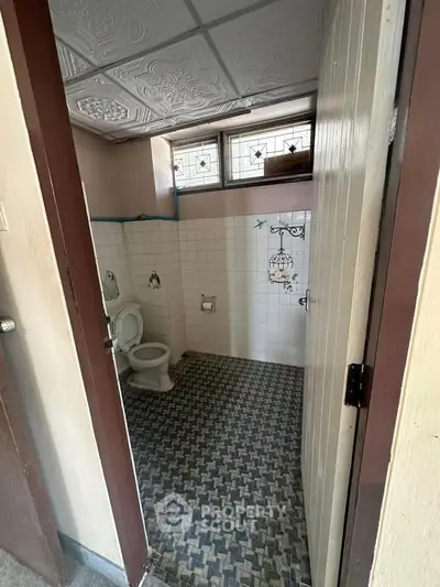 Charming vintage bathroom with patterned floor tiles and decorative wall art.