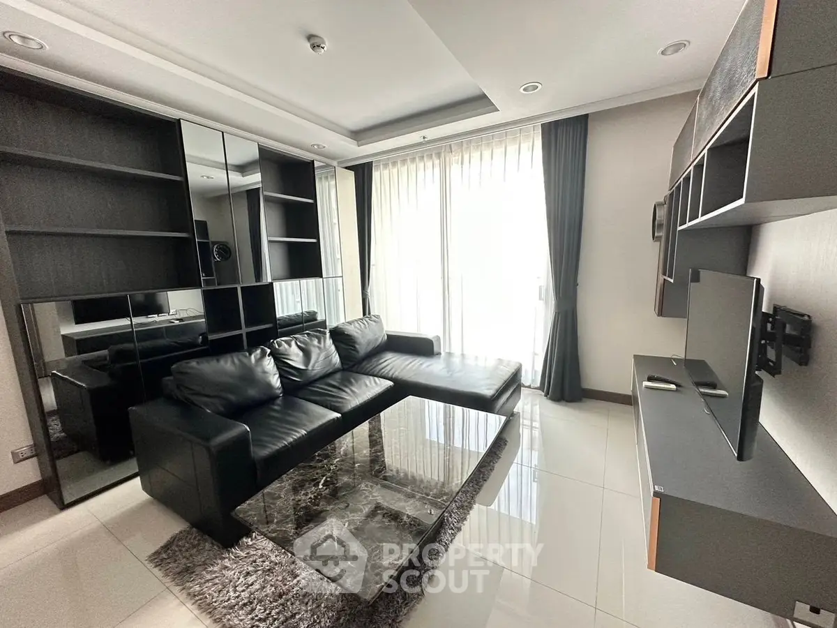 Modern living room with sleek black furniture and large windows for natural light.