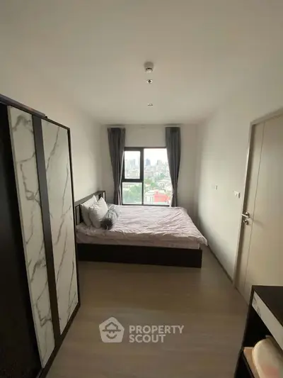 Modern bedroom with city view, featuring a stylish bed and wardrobe, perfect for urban living.