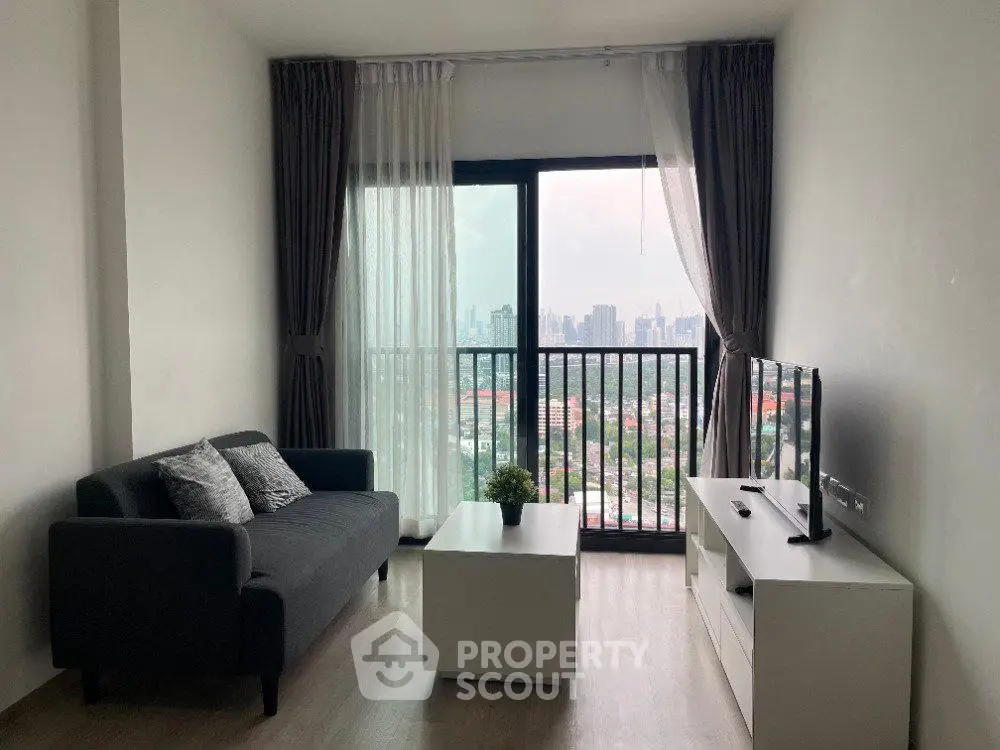 Modern living room with city view, featuring sleek furniture and large windows for natural light.