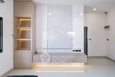 Modern minimalist living room with built-in shelving and marble accent wall