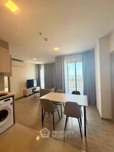 Modern living room with dining area and natural light, featuring a washing machine and stylish decor.