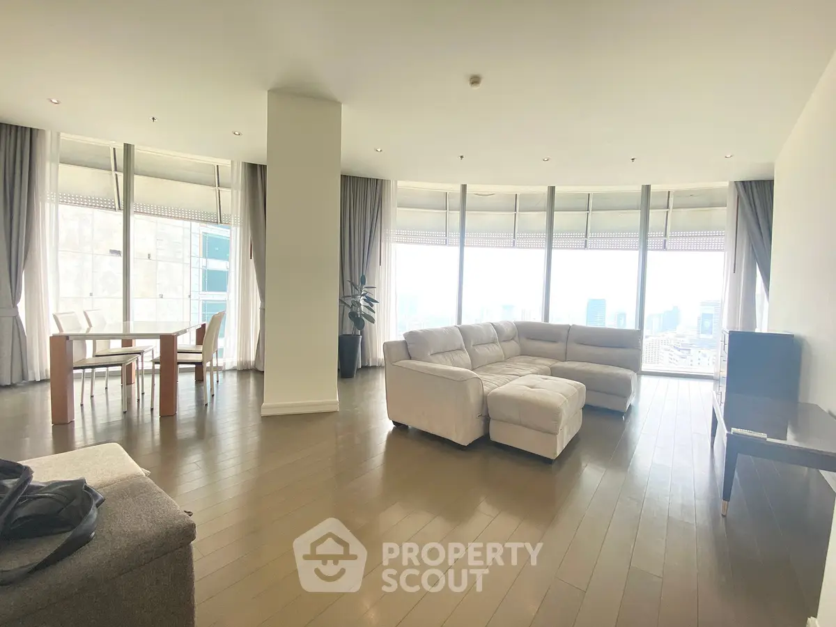 Spacious modern living room with panoramic city views and elegant furnishings.