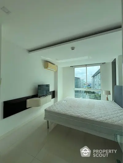 Modern bedroom with large window and city view in high-rise apartment