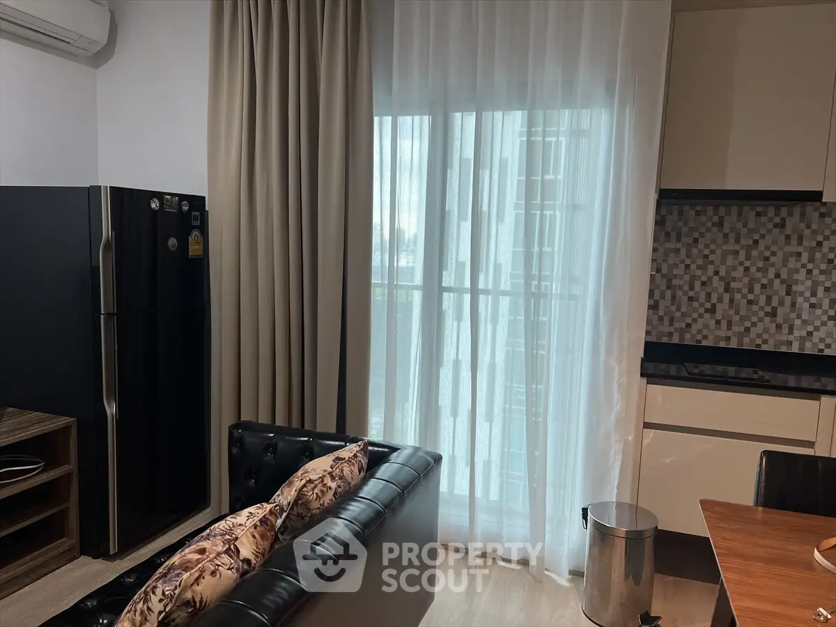 Modern living room with sleek kitchen and balcony view, featuring stylish decor and natural light.