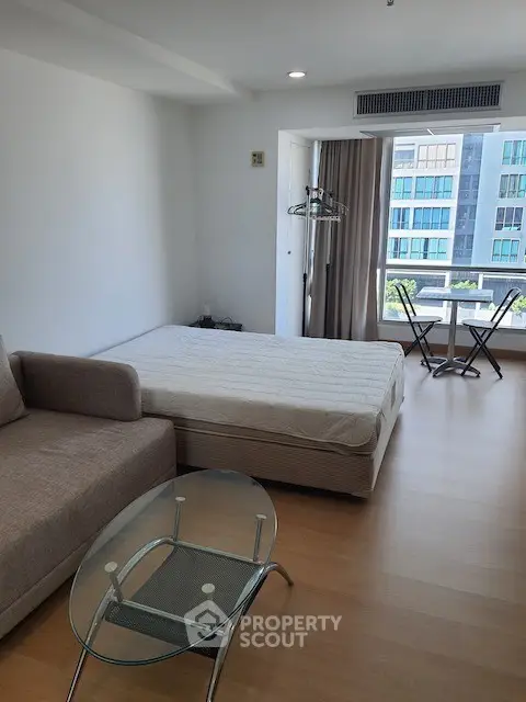 Modern studio apartment with large window and minimalist furnishings