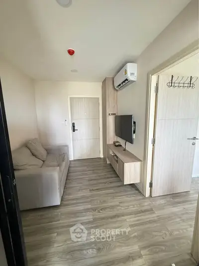 Modern living room with sleek furniture and wall-mounted TV in a cozy apartment.