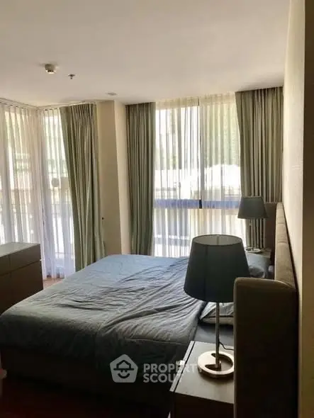 Spacious bedroom with large windows and elegant curtains in a modern apartment.