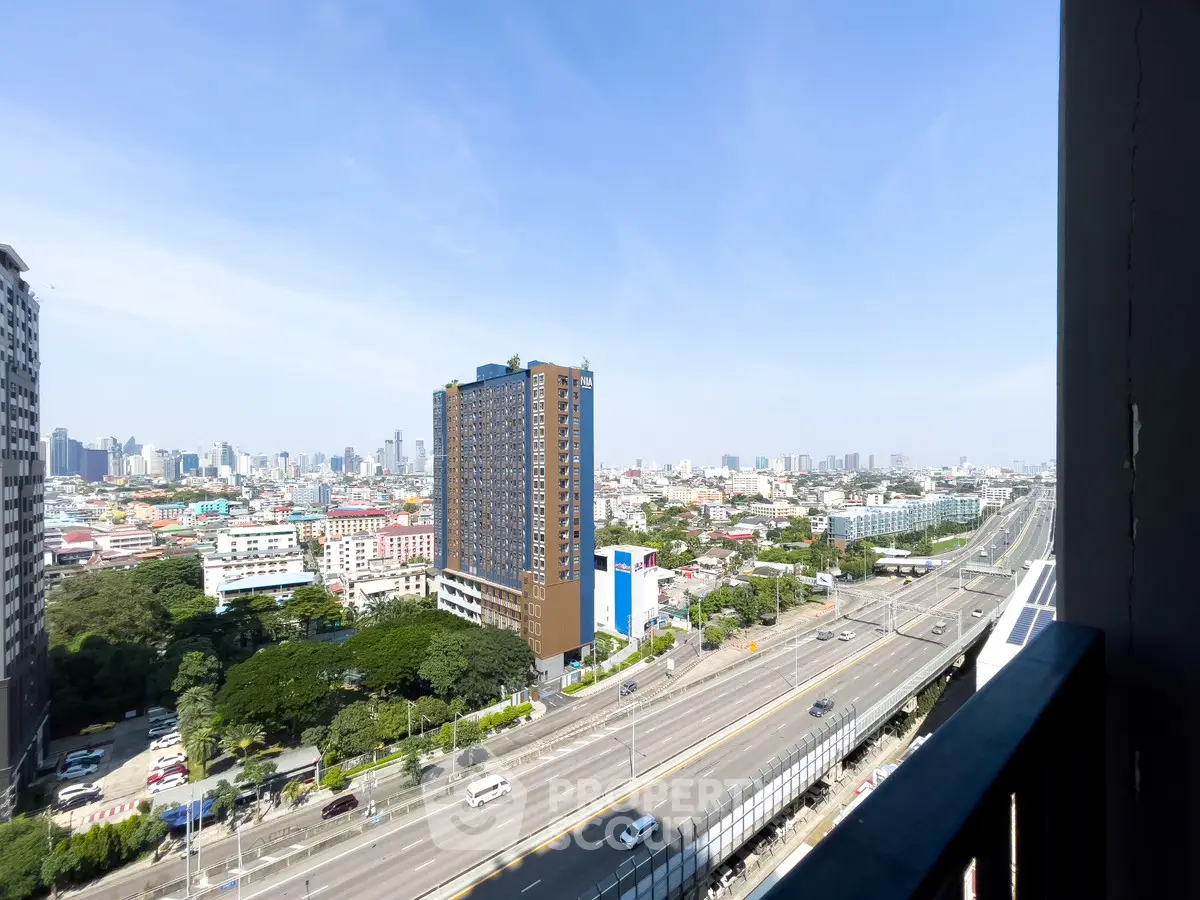 Stunning cityscape view from high-rise balcony overlooking urban skyline and highway.