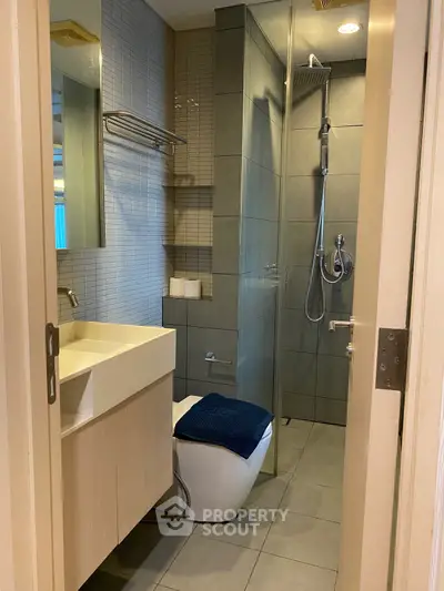 Modern bathroom with sleek fixtures and glass shower enclosure in a contemporary apartment.