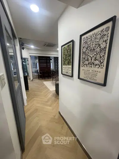 Stylish hallway with elegant wood flooring and framed art leading to a cozy living area.