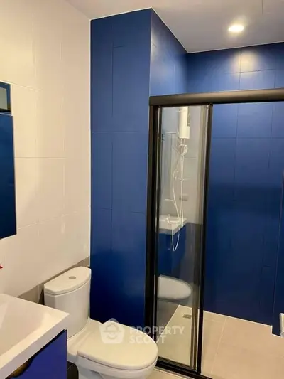 Modern bathroom with blue tiles and glass shower enclosure