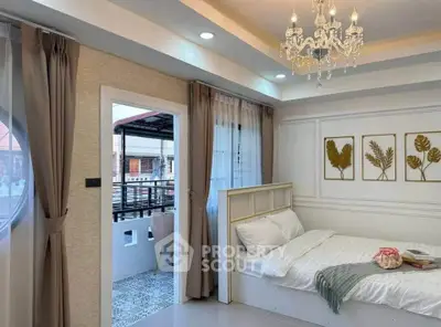 Charming bedroom with elegant chandelier and balcony access, perfect for cozy living.