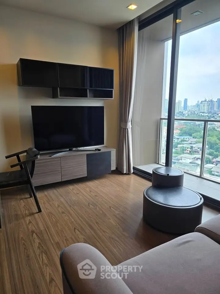 Modern living room with large TV and city view from balcony