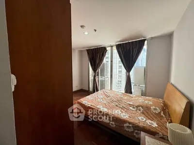 Cozy bedroom with large windows and city view, featuring a wooden bed and floral bedding.