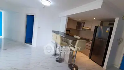 Modern kitchen with open layout and sleek bar seating in a bright apartment.
