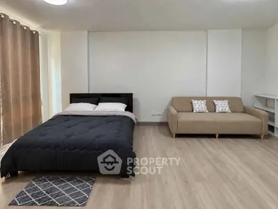 Spacious bedroom with modern decor featuring a cozy bed and stylish sofa, perfect for relaxation.