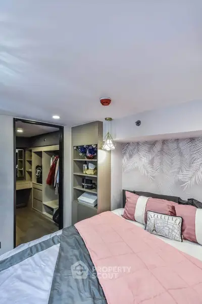 Modern bedroom with stylish decor and walk-in closet, featuring cozy bedding and elegant lighting.