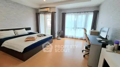 Spacious modern bedroom with natural light and workspace, perfect for comfort and productivity.