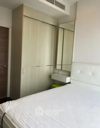 Modern bedroom with sleek wardrobe and stylish mirror in a cozy apartment.