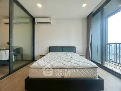 Modern bedroom with large windows and balcony offering stunning city views.