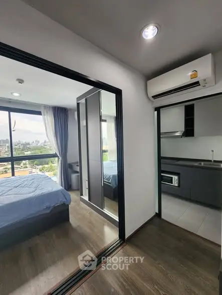 Modern apartment interior with bedroom and kitchen, featuring large windows and sleek design.