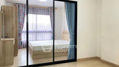 Spacious bedroom with large window and mirrored wardrobe in modern apartment.