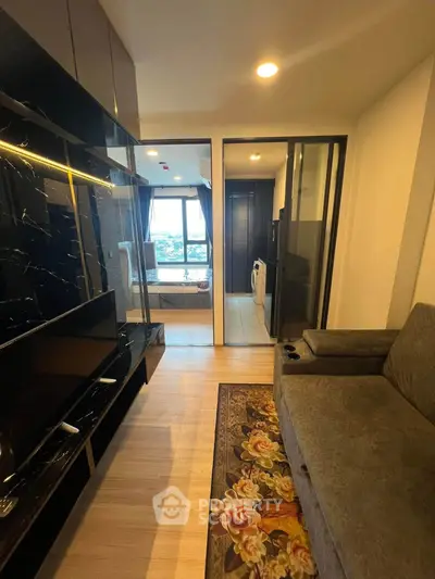 Modern living room with stylish decor and view of bedroom through sliding glass doors.