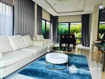 Luxurious modern living room with elegant furniture and large windows overlooking lush greenery.