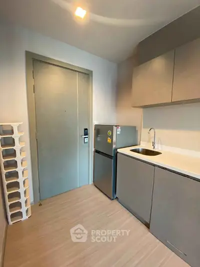 Modern compact kitchen with sleek cabinetry and mini fridge